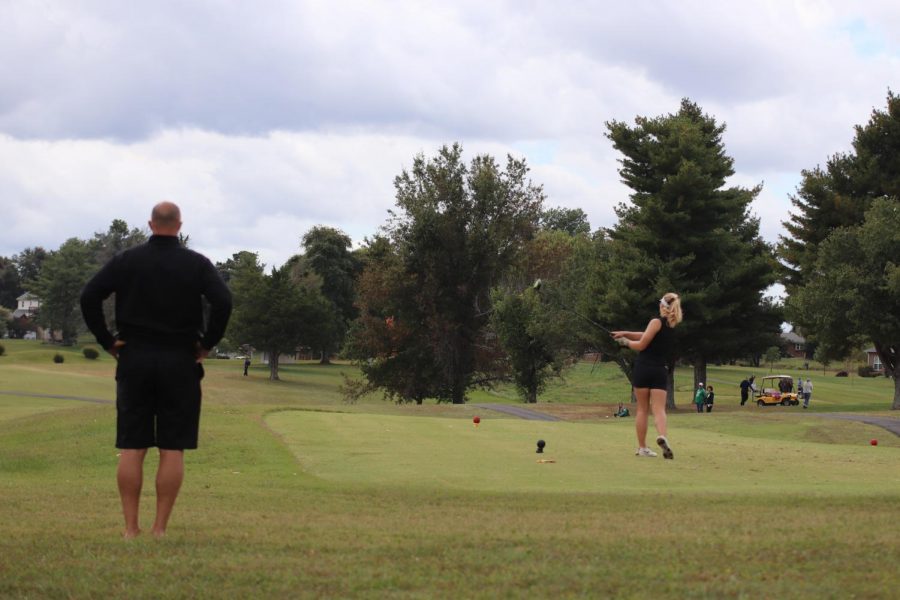 Coach Larry Steinmetz watches as sophomore Macie Brown tees off. Browns improvement from last season has been large and has served as motivation for her all season. It helps motivate me to continue working for the next two (years) to perform even better, Brown said. 