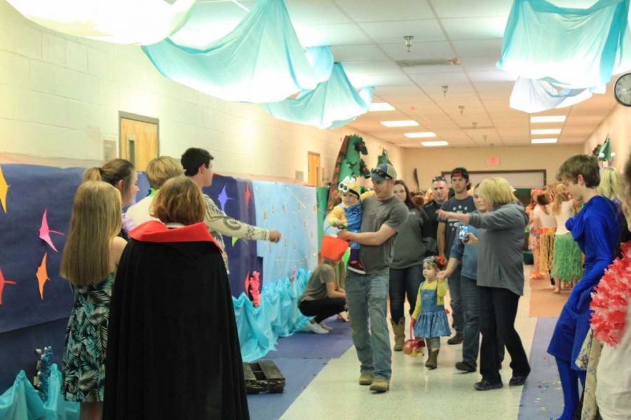 Parents and children walk down the halls while attending Halloween in the Halls.