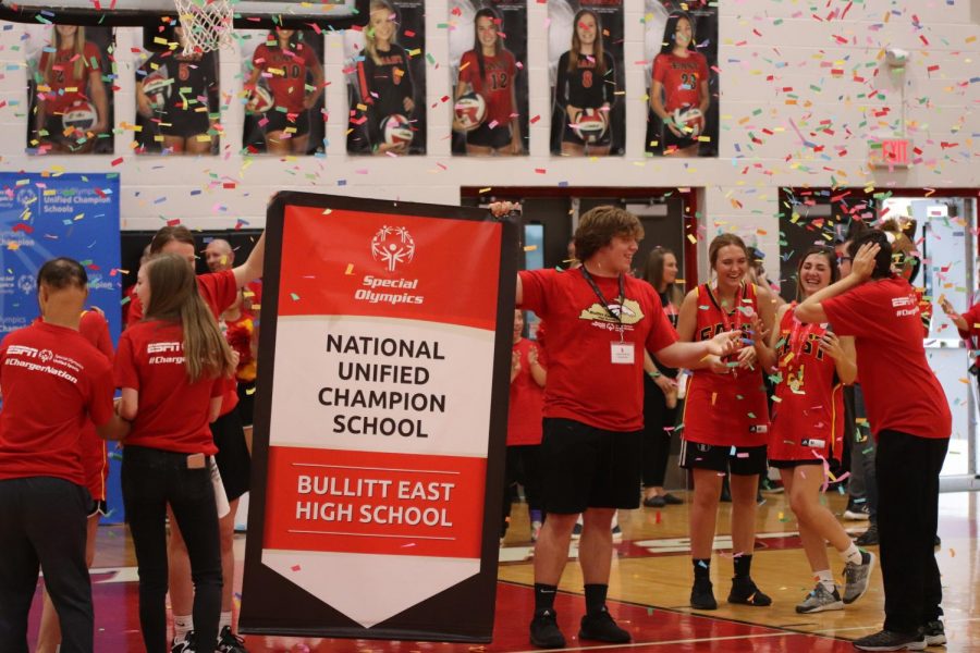 Senior Conner Groves holds the National Unified Champion School banner in front of the crowd. ESPN and Special Olympics presented this banner during the assembly. Groves said, It was very cool seeing the kids in the club so excited and for the whole day to just be about them.