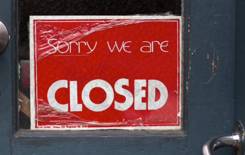 A "closed" sign being put on display in the window of a business.