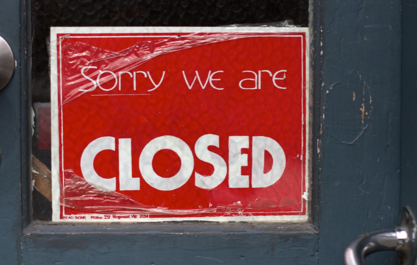 A closed sign being put on display in the window of a business.