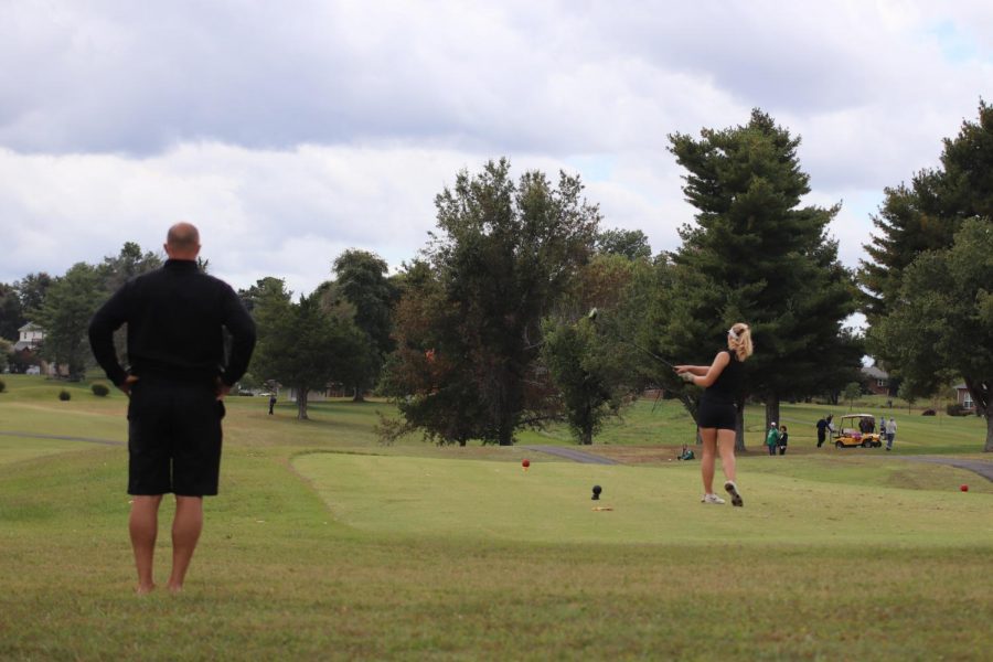 Coach Larry Steinmetz watches as sophomore Macie Brown tees off. Brown's improvement from last season has been large and has served as motivation for her all season. "It helps motivate me to continue working for the next two (years) to perform even better," Brown said. 