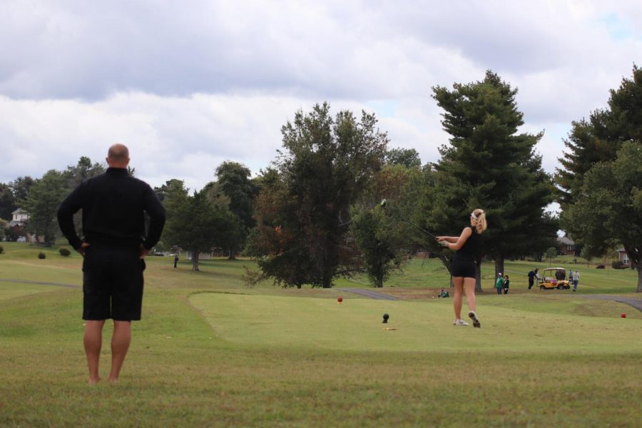 Coach+Larry+Steinmetz+watches+as+sophomore+Macie+Brown+tees+off.+Browns+improvement+from+last+season+has+been+large+and+has+served+as+motivation+for+her+all+season.+It+helps+motivate+me+to+continue+working+for+the+next+two+%28years%29+to+perform+even+better%2C+Brown+said.+