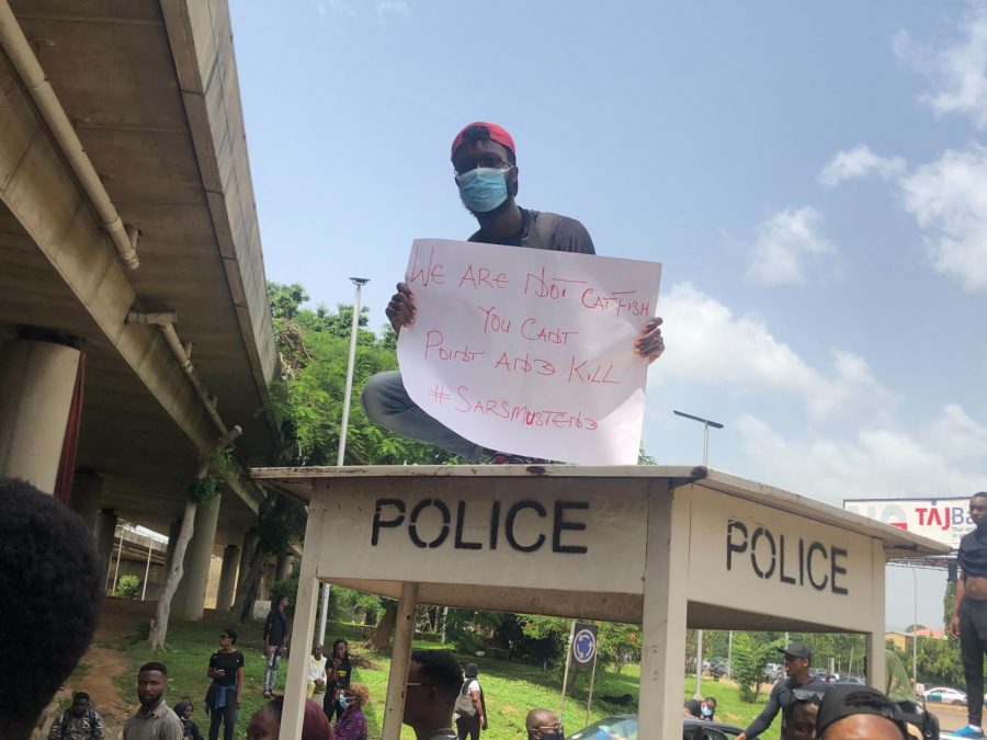 Nigerian man peacefully protesting holding sign stating, "We are not catfish you can't point and kill #SARSmustend"