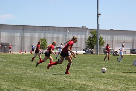 Three players rush near the ball. This season, the team has been focusing more and more on communication. "For the rest of the season I think we need to work on our communication skills because it's something we've really been struggling with during games," junior Tessa Tibone said. 