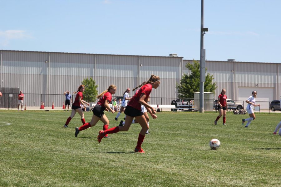 Three players rush near the ball. This season, the team has been focusing more and more on communication. "For the rest of the season I think we need to work on our communication skills because it's something we've really been struggling with during games," junior Tessa Tibone said. 